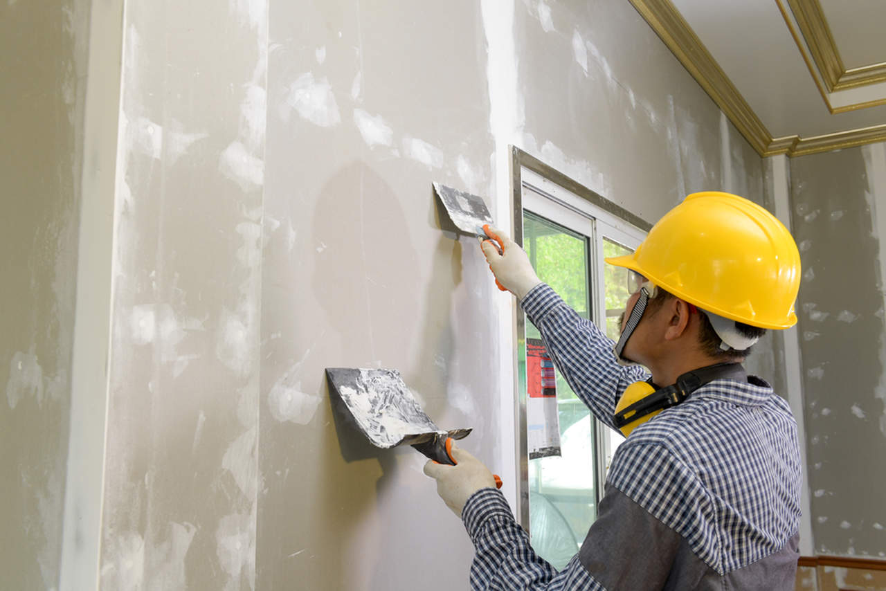 worker making plaster into the wall