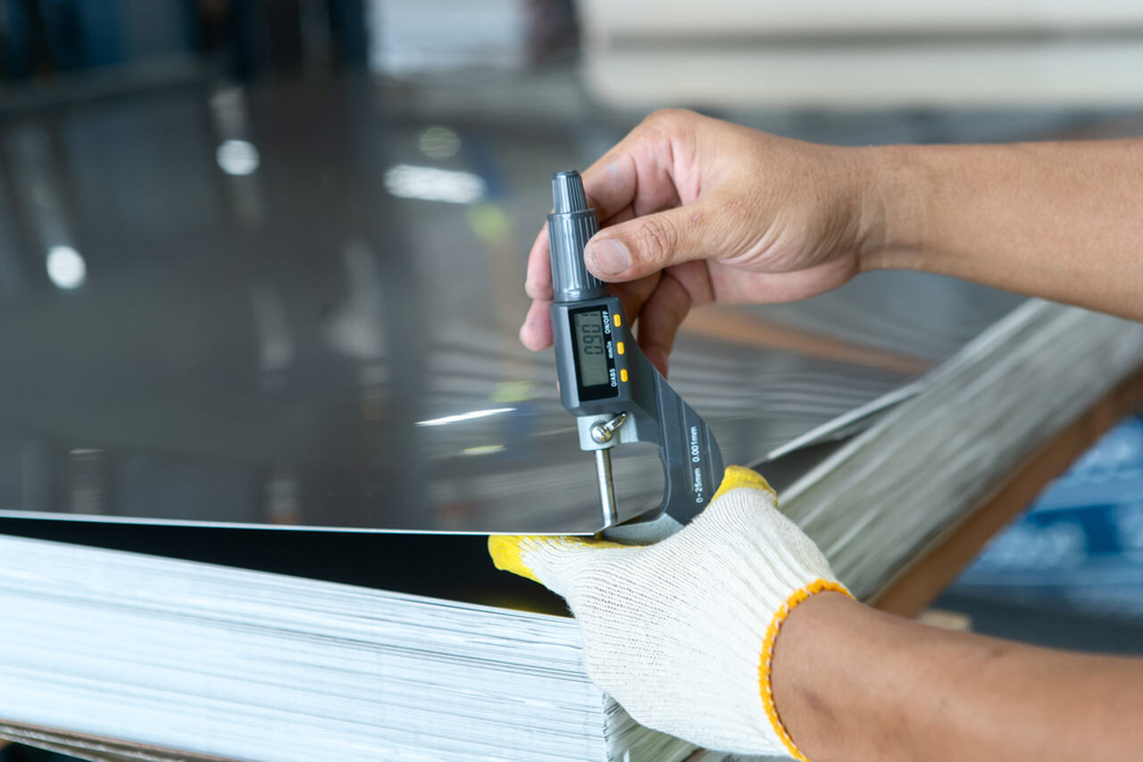 worker measuring sheet metal thickness with a machine